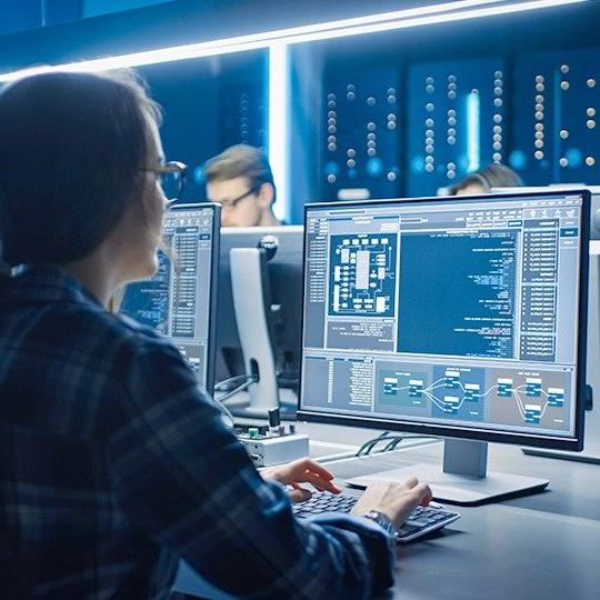 Three employees in a secured network room working on cybersecurity protection on desktop computers